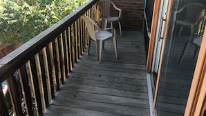 A wooden deck with two plastic chairs, a brick wall, and a glass door. - 1,800sf 3 Stories with 8 beds townhome (Casper)