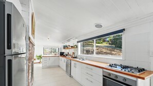 Una cocina moderna con armarios blancos, encimera de madera y un ventanal con vistas al exterior.