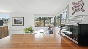 Una cocina moderna con una mesa de comedor de madera, ventanas amplias y un cartel en la pared que dice "EAT DINER DRINK".