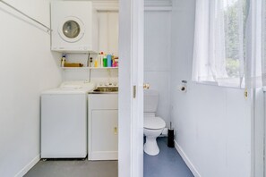 Ett litet, praktiskt utrymme för tvätt med tvättmaskin, torktumlare och toalett.