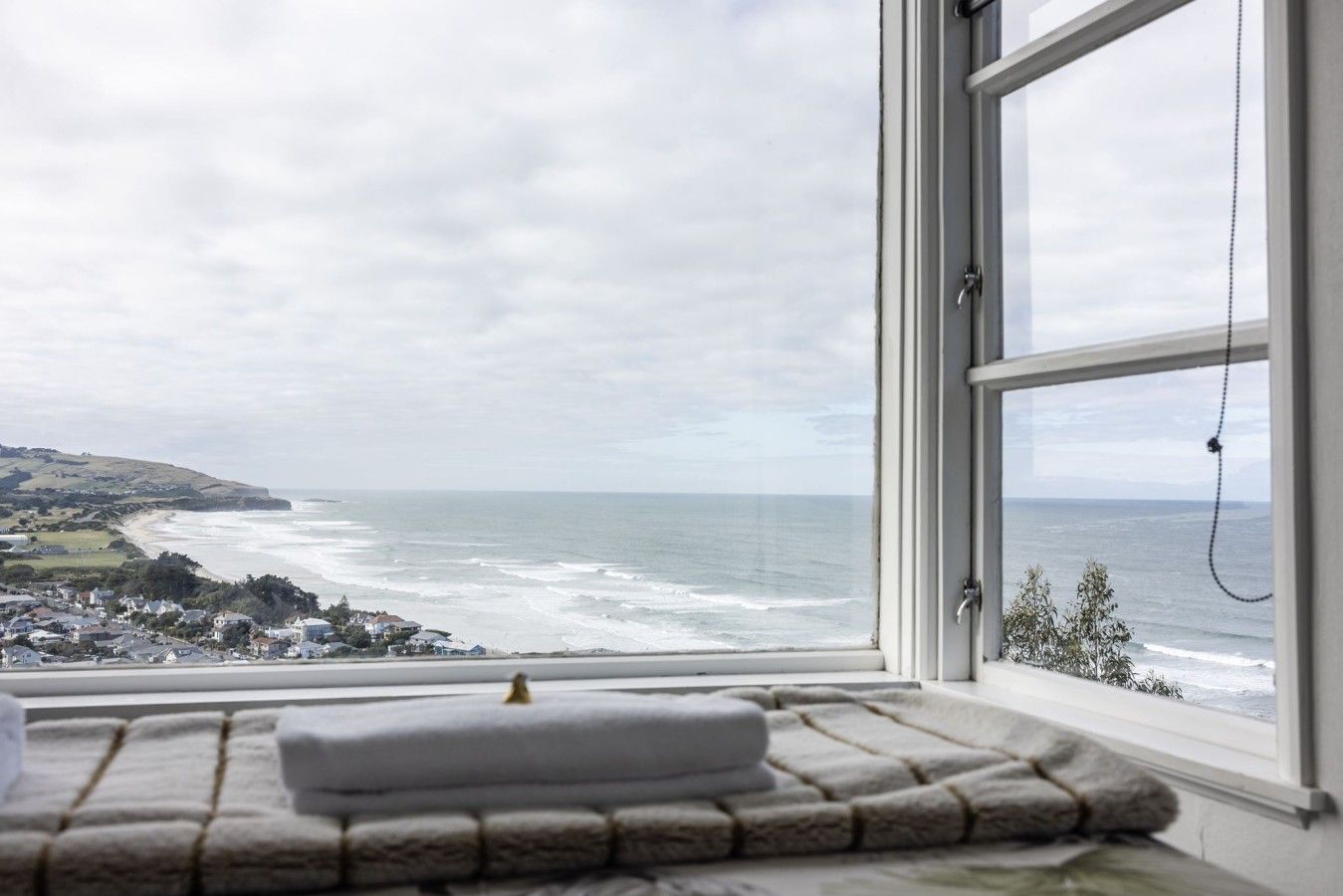 Quarto com vista para o mar, uma janela e uma toalha no peitoril.