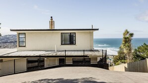 A modern two-story building with a balcony overlooking a coastal view. - St Clair Heights-Ocean views (Dunedin)