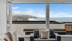 A modern living room with a sofa, a coffee table, and a view of the ocean. - St Clair Heights-Ocean views (Dunedin)