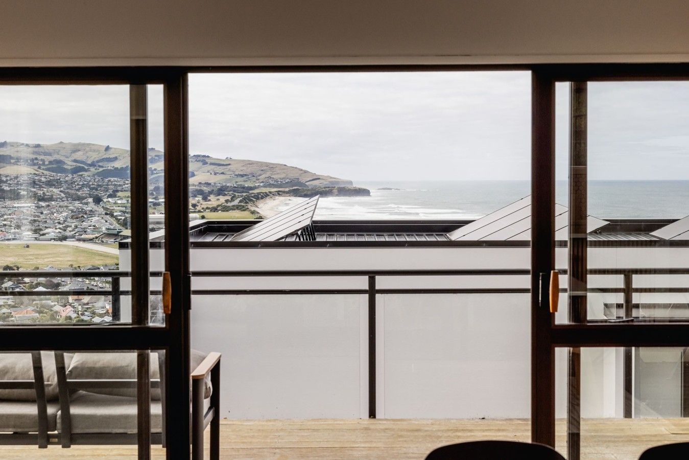 Un balcón con vistas a un paisaje costero, que incluye colinas y una playa.