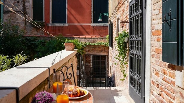 Un petit espace extérieur aménagé pour prendre les repas, avec une table, des chaises et une plante en pot.