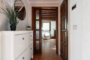 A hallway with a white dresser, a potted plant, and a door leading to a bathroom with a shower and a towel rack. - Ca' del Majo (Venezia)