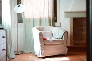 A room with a sofa, a floor lamp, a window with curtains, a fireplace, and a tiled floor. - Ca' del Majo (Venezia)