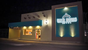 Exterior de un hotel con un gran letrero iluminado que dice "Cuatro Misiones Hotel".