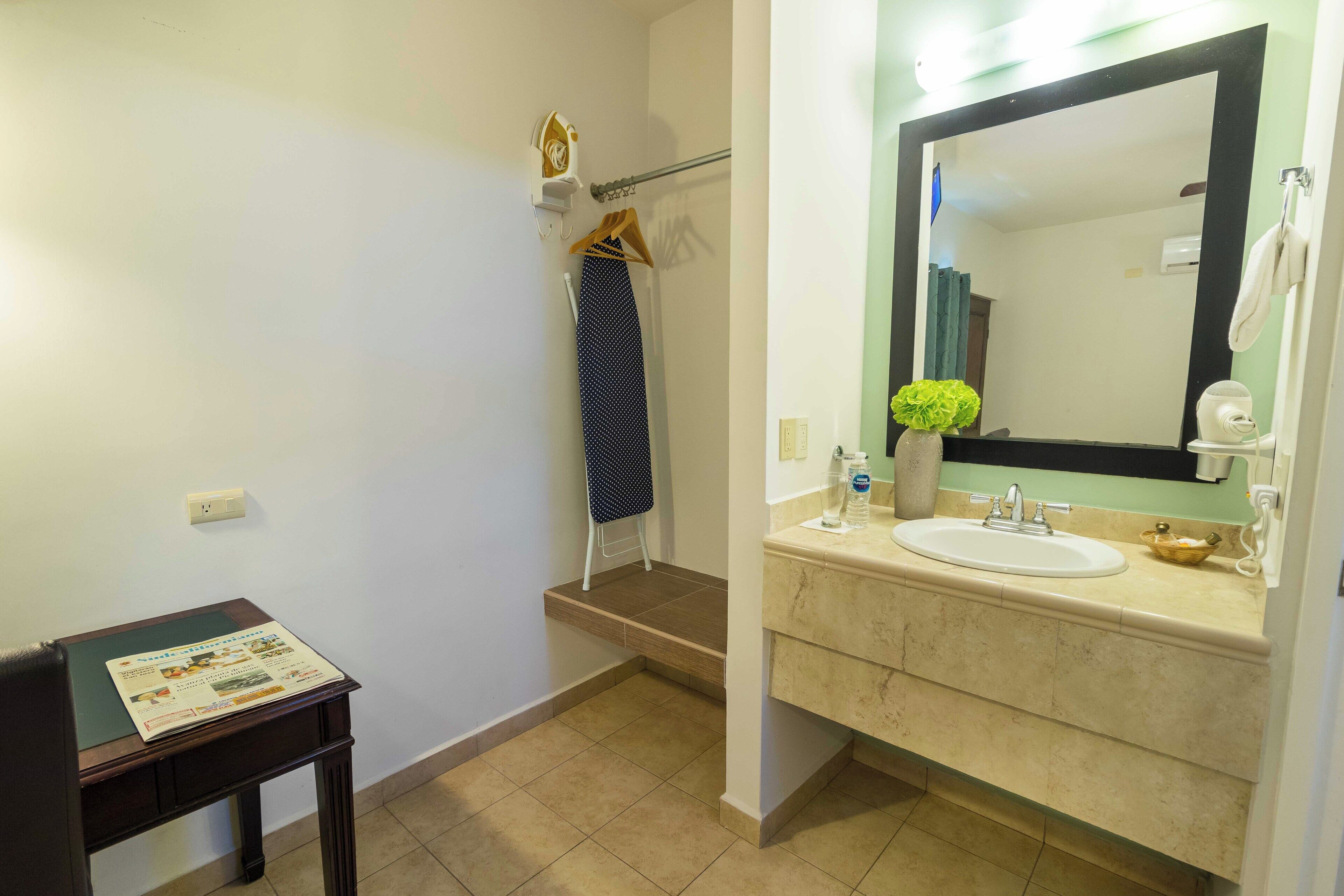 A bathroom with a sink, mirror, towel rack, and a small table with a magazine.