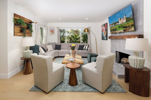 A modern living room with a sectional sofa, two armchairs, a coffee table, and a fireplace.