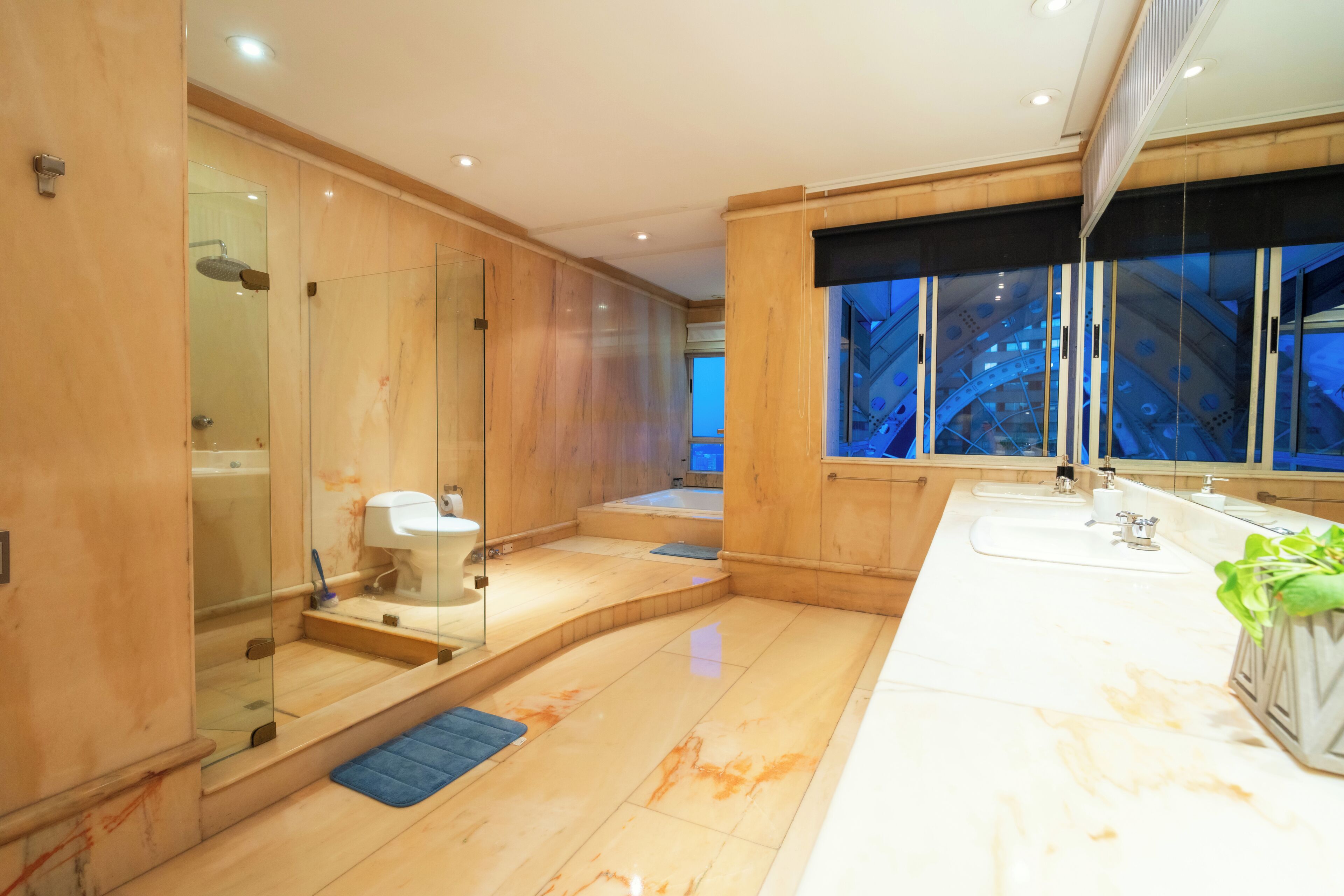 Een moderne badkamer met een douchecabine van glas, een badkuip, een groot wastafel en een raam met uitzicht.