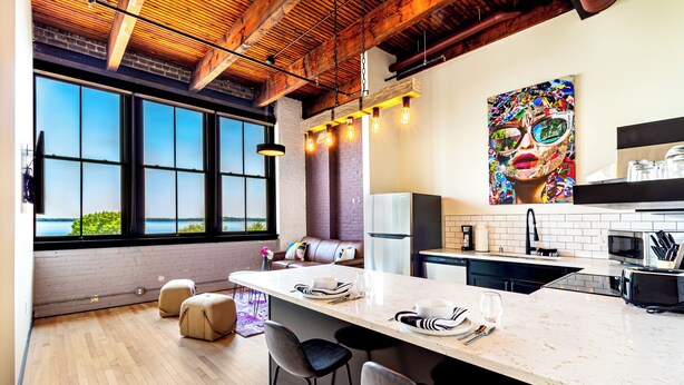 A modern kitchen with a large island, bar stools, and a view of the outdoors.