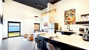 A modern kitchen with a large island, bar stools, a refrigerator, and a view of the sea. - One Bedroom King with views of the heart of downtown. (Madison)