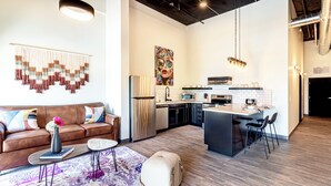 A modern living room with a brown sofa, a coffee table, and a rug. - One Bedroom King with views of the heart of downtown. (Madison)