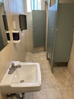 Un baño con lavamanos, espejo, secador de manos y retrete.