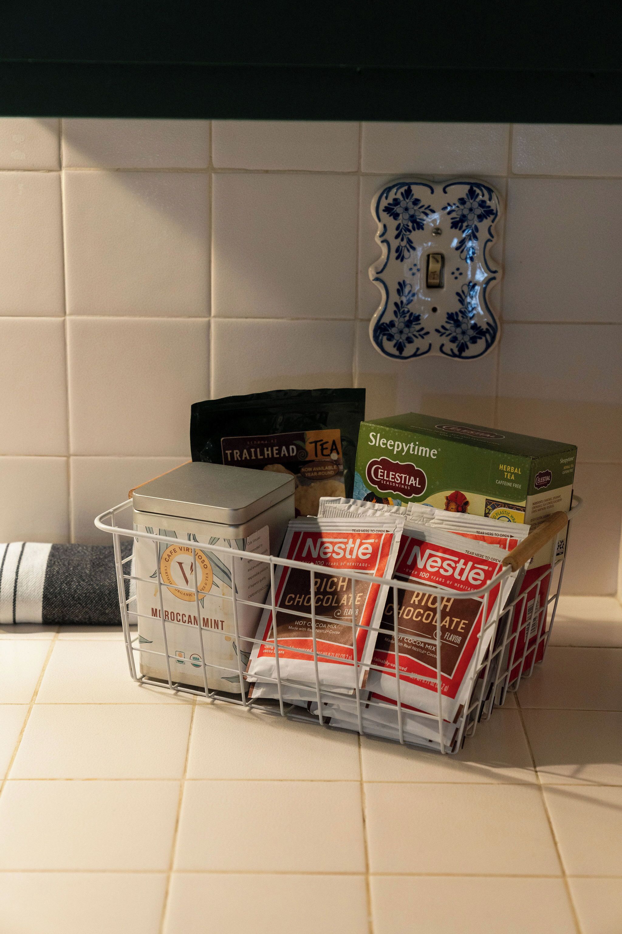 A kitchen counter with a metal basket containing various food items and boxes.