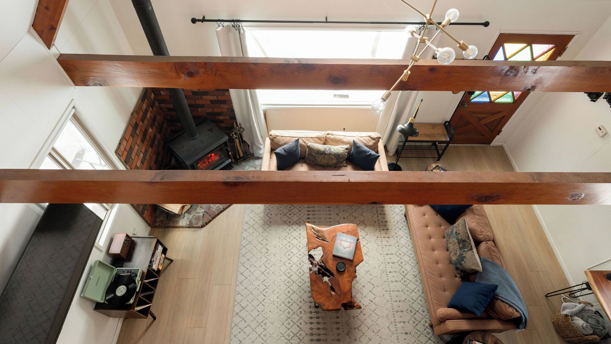 Un espacio habitable tipo loft con vigas de madera a la vista, una chimenea, un sofá y una mesa de centro.