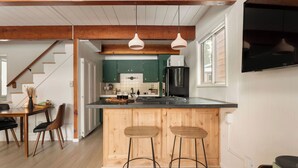 Una cocina moderna con armarios de madera, un refrigerador negro y una zona de bar con taburetes.