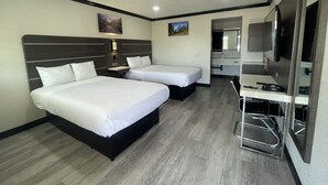 Een hotelkamer met twee bedden, een bureau, een spiegel en een televisie.
