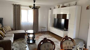 A modern living room with a sofa, a round table, a TV, and a cabinet.