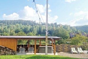 Ein Holzhaus mit überdachter Terrasse, Außenbestuhlung und Whirlpool.
