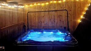 A hot tub with a wooden interior and string lights.