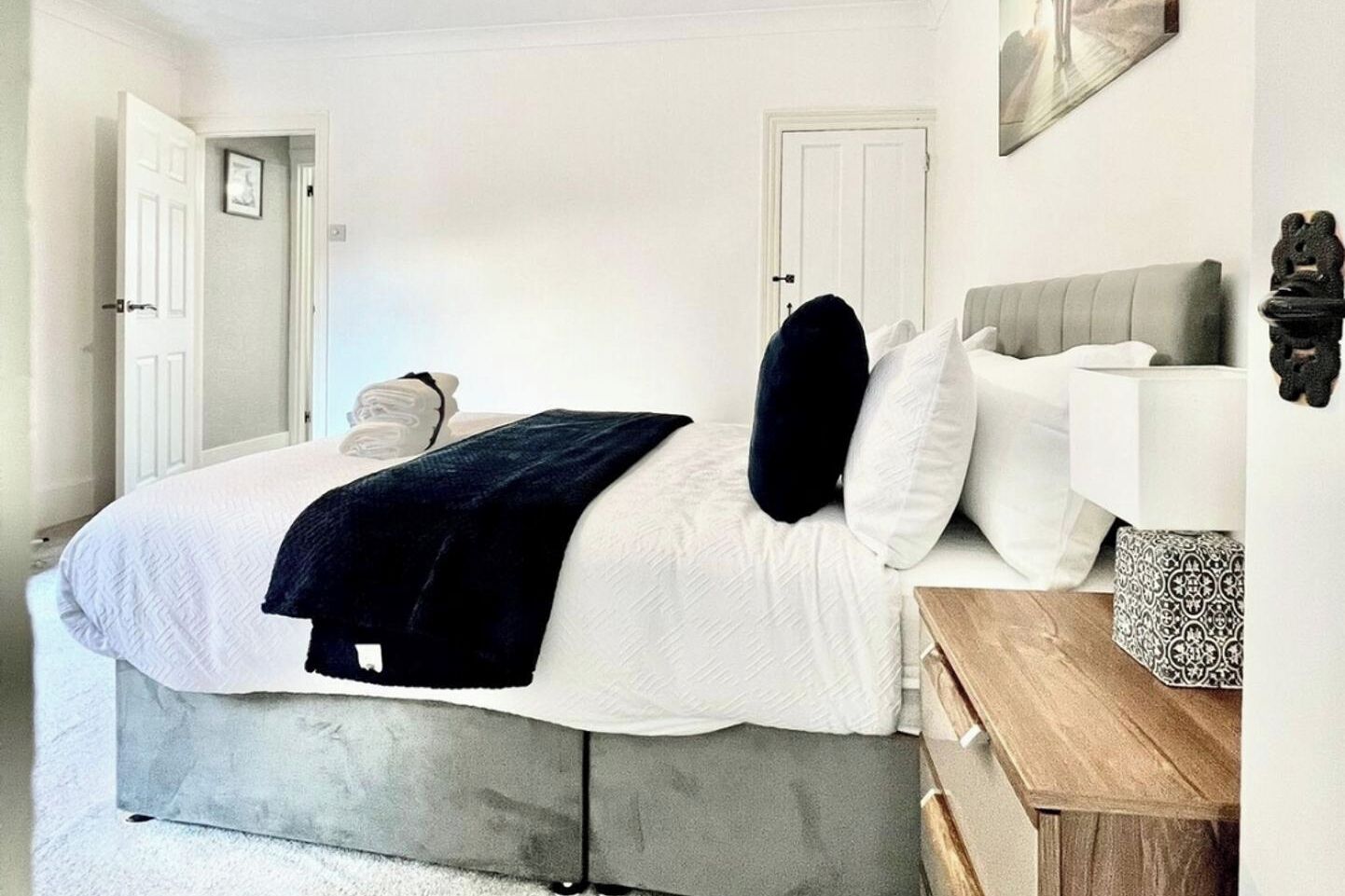 A bedroom with a bed, bedside table, and a door.