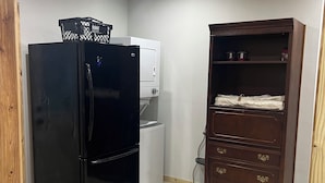 A compact kitchen with a black refrigerator, a white washing machine, and a wooden cabinet with drawers.