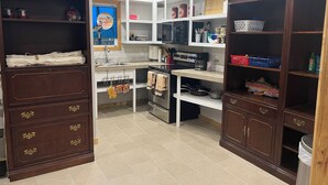 A kitchen with wooden cabinets, white shelves, and a tiled floor.