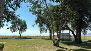 Un espacio al aire libre con césped, árboles y una estructura de madera.