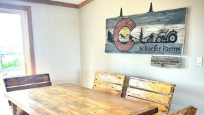 Un comedor con una mesa y bancos de madera, un ventilador de techo y un letrero en la pared que dice "Schaefer Farms".