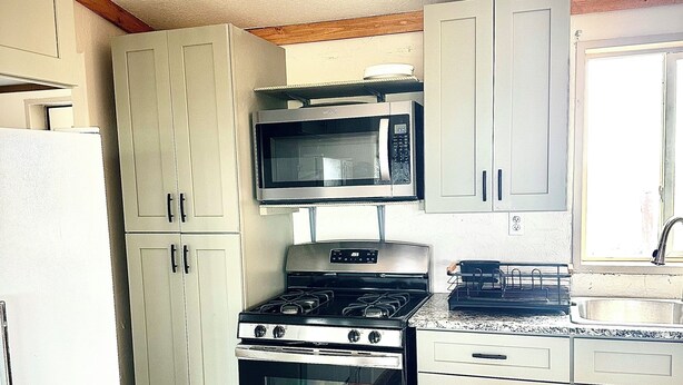 Una cocina compacta equipada con microondas, horno y estufa.