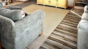 Sala de estar con ventilador de techo de madera, un televisor de pantalla plana sobre un mueble de madera y un ventanal grande.