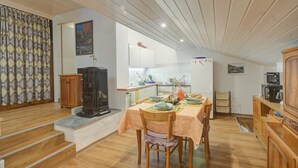 Un coin repas avec une table dressée pour deux personnes, un buffet en bois et une cuisine en arrière-plan.