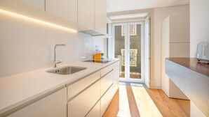 Une cuisine moderne avec des meubles blancs, un évier en acier inoxydable et un plancher en bois.