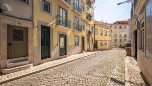 Une rue pavée bordée de bâtiments jaunes, chacun ayant une porte et des fenêtres vertes.