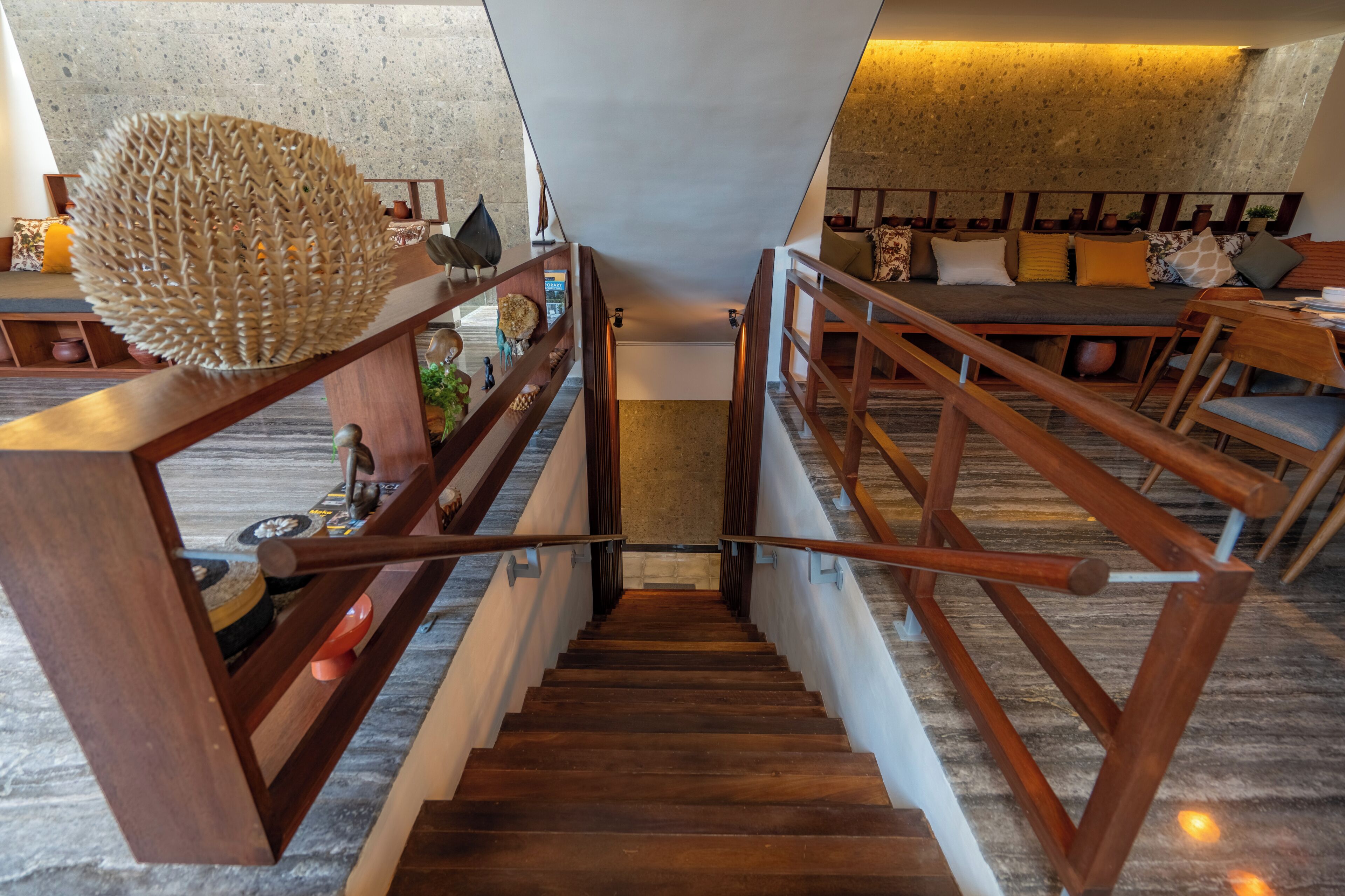 Un escalier en bois mène à un espace de vie comprenant un canapé et des coussins.