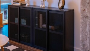A black console table with a mounted TV above it, a clock, and decorative items. - Pleasure and Modernity: Dream Apartment for Rent in Saint-Roch, Quebec! (Québec)