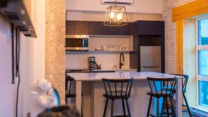 A modern kitchen with a central island, bar stools, and a checkered floor. - Pleasure and Modernity: Dream Apartment for Rent in Saint-Roch, Quebec! (Québec)