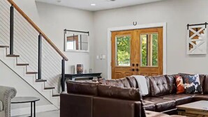 A modern living room with a staircase, a large sectional sofa, and a wooden door.