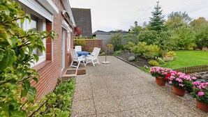 Een terras met een bakstenen muur, buitenmeubels en plantenpotten.