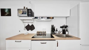 Una cocina moderna con estufa integrada, un lavamanos y una encimera con utensilios de cocina.