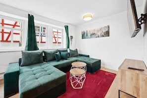 Un salon moderne avec un canapé d’angle, une table basse ronde et un tapis rouge.