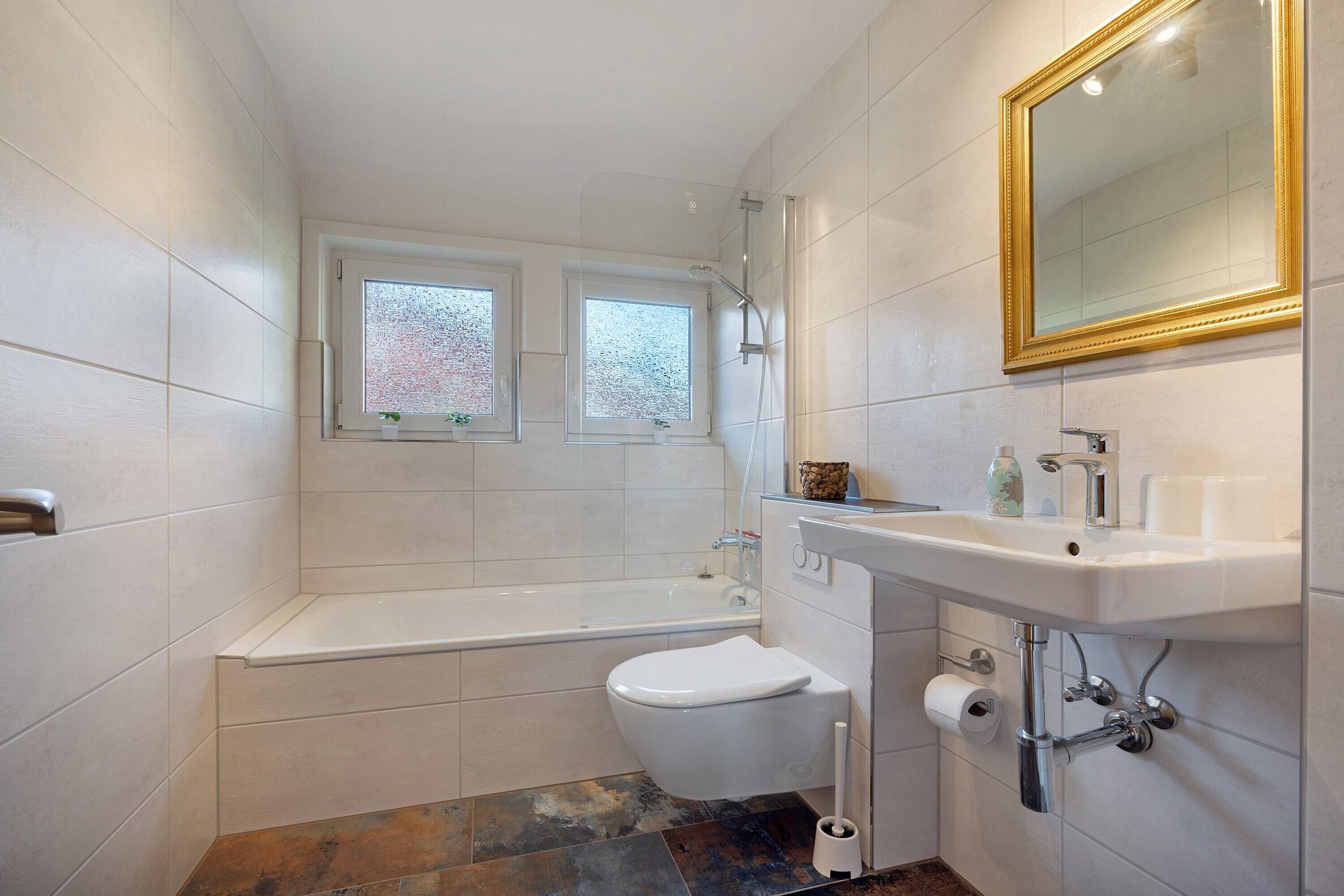 Een badkamer met een bad, toilet, wastafel en een raam.