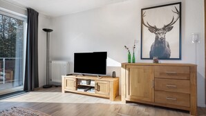 Un soggiorno moderno con TV a schermo piatto, mobiletto in legno e un'ampia opera d'arte a tema cervo appesa al muro.