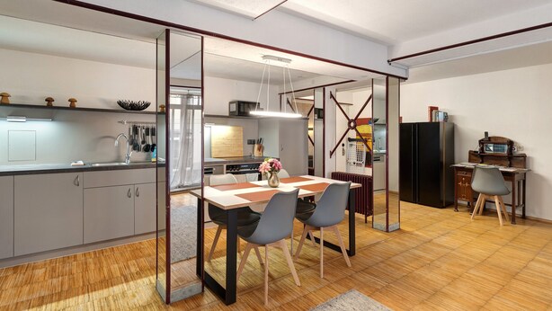 A modern kitchen with a dining area, wooden flooring, and a large mirror.