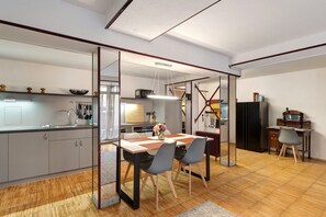 Une cuisine moderne avec un coin repas, un plancher en bois et un grand miroir.
