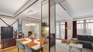 A modern living space with a dining area, sofa, and kitchen.