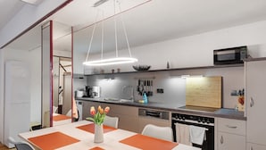 A modern kitchen with a dining table, chairs, a microwave, and a sink.