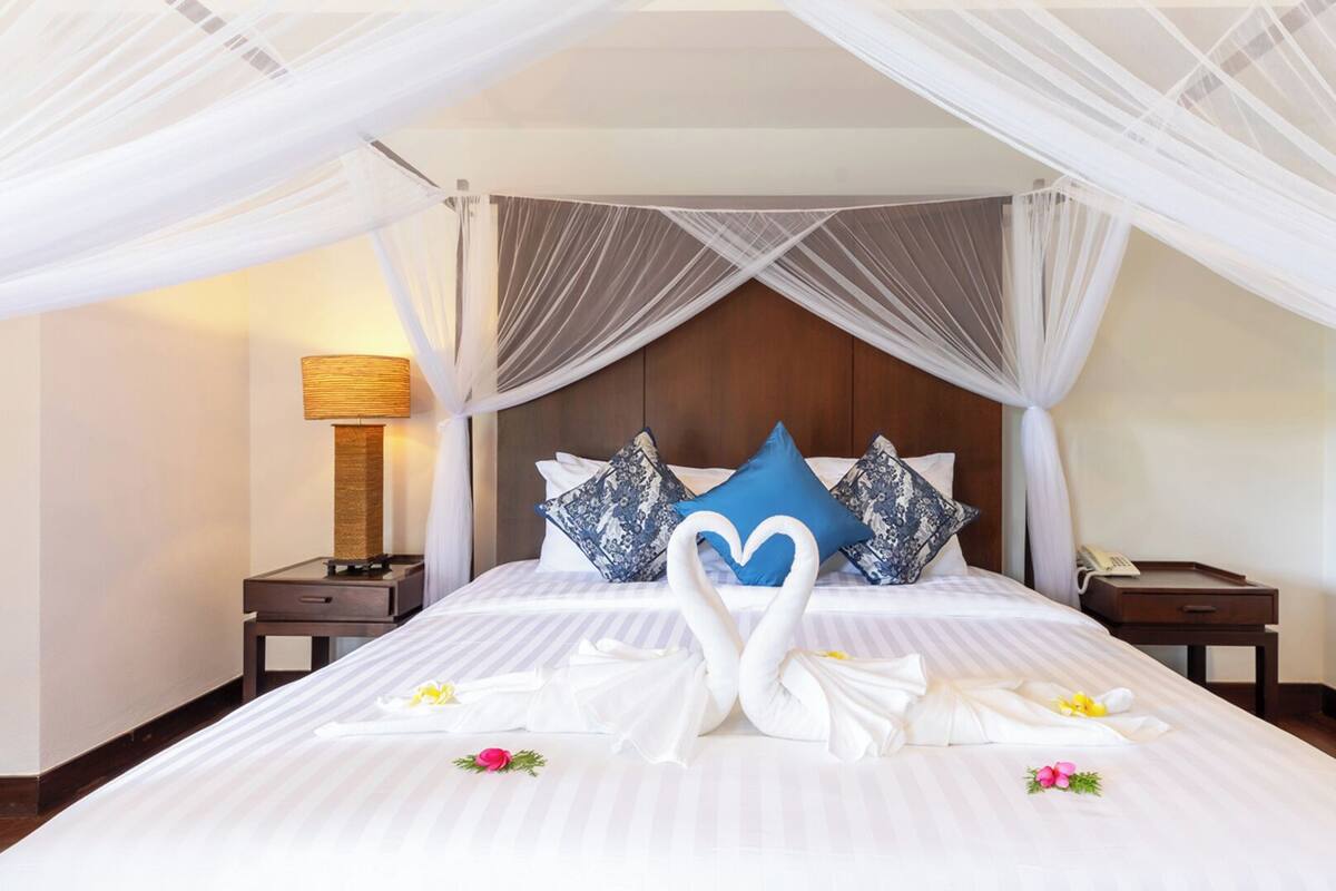 A hotel room with a bed, a nightstand, a lamp, and a decorative wall piece.